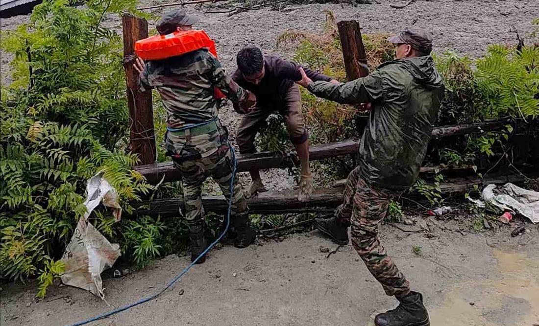 Esta fotografía, tomada el 5 de agosto de 2025 y difundida por el Ejército de la India, muestra a personal de seguridad rescatando a un residente local (C) de un denso lodo durante una operación de búsqueda y rescate tras un aguacero que causó un enorme deslizamiento de tierra en el estado indio de Uttarakhand. Una inundación repentina, que desató un torrente de lodo, azotó una localidad de la región del Himalaya el 5 de agosto, arrasando un valle montañoso antes de demoler edificios y causar la muerte de al menos cuatro personas. Foto: AFP