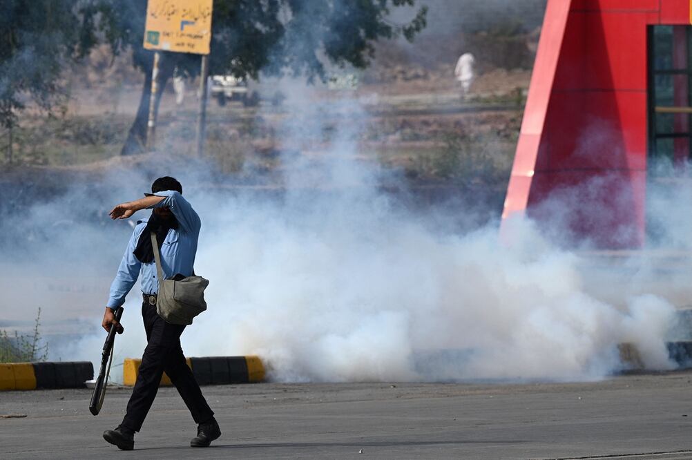 Un policía camina por una carretera en medio de gases lacrimógenos lanzados para dispersar a los activistas del partido Pakistan Tehreek-e-Insaf y a los partidarios del exprimer ministro Imran Khan. Foto: AFP