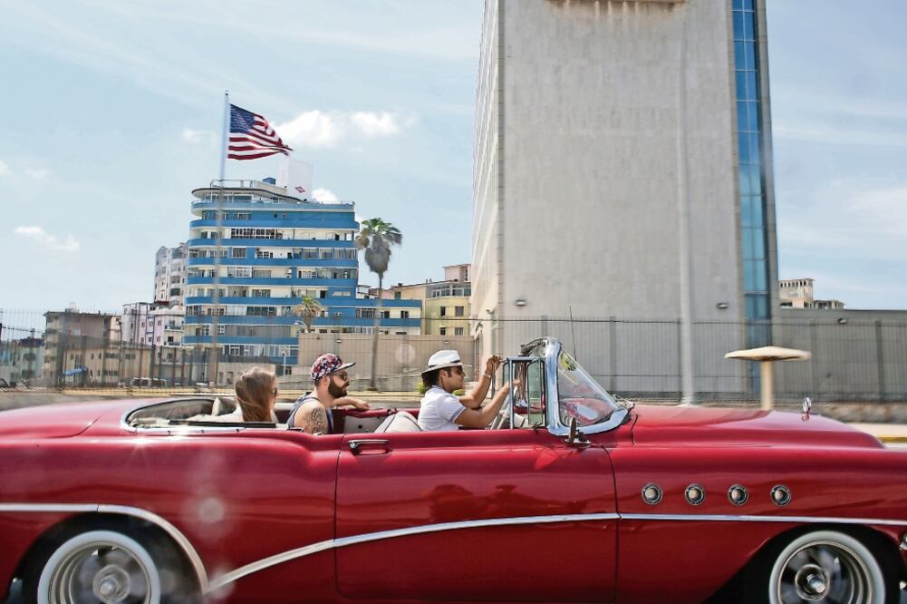 Turistas pasean en un auto antiguo frente a la embajada de Estados Unidos en La Habana. Los días lunes y martes, Obama estará en la isla para reunirse con el presidente Raúl Castro, pero también con líderes de la oposición (ALEXANDRE MENEGHINI. REUTERS)