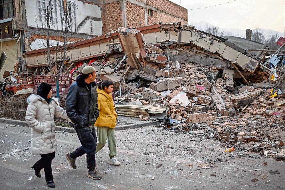 Lugareños caminan junto a un edificio colapsado, en Dahejia, tras el terremoto en el noroeste de China. Foto: Pedro Pardo | AFP