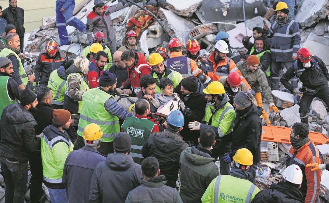 Elementos de búsqueda y rescate transportan a un niño y a sus padres después de que fueron evacuados de un edificio derrumbado en Hatay, sureste de Turquía, tras el terremoto de magnitud 7.8.