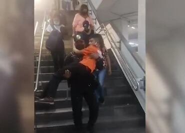 Policía de CDMX carga a niño con dificultades para caminar y lo ayuda a bajar escaleras del Metro