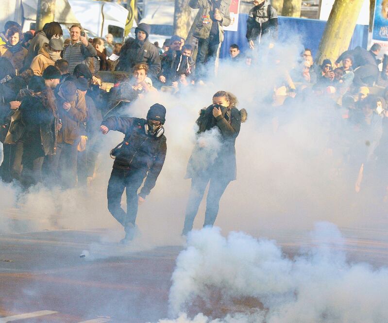 Un francés avienta una granada de gas lacrimógeno en las protestas por la reforma de pensiones, en Burdeos. Foto: NICOLAS TUCAT. AFP