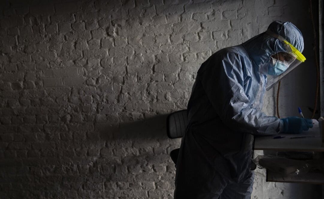 A doctor, wearing full protective equipment, takes notes as he screens a patient with symptoms of coronavirus - Photo: Francisco Seco/AP
