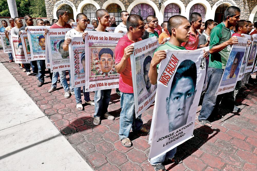 Personas sosteniendo carteles con las rostros de los 43 estudiantes de Ayotzinapa. Fotografía: Cristopher Rogel / EL UNIVERSAL 