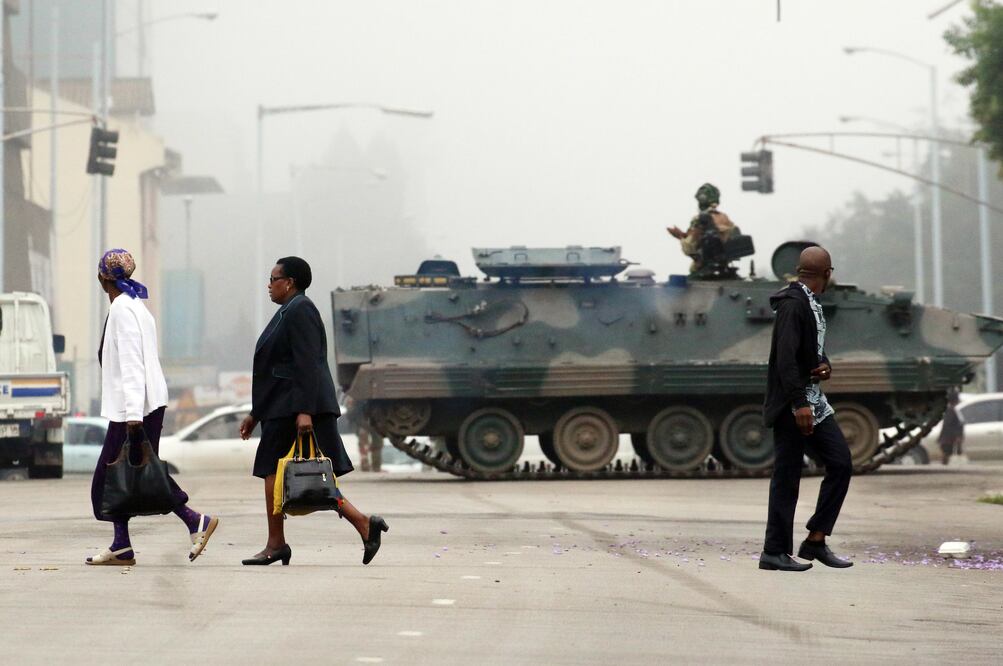 Personas caminan frente a un vehículo blindado en una calle en Harare, capital of Zimbabue (Foto: Xinhua)