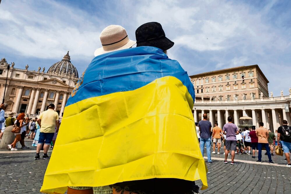 Fieles con una bandera ucraniana escuchan al papa Francisco, mientras dirige el Ángelus en la Plaza de San Pedro, el 27 de agosto pasado. Foto: Massimo Percossi / EFE