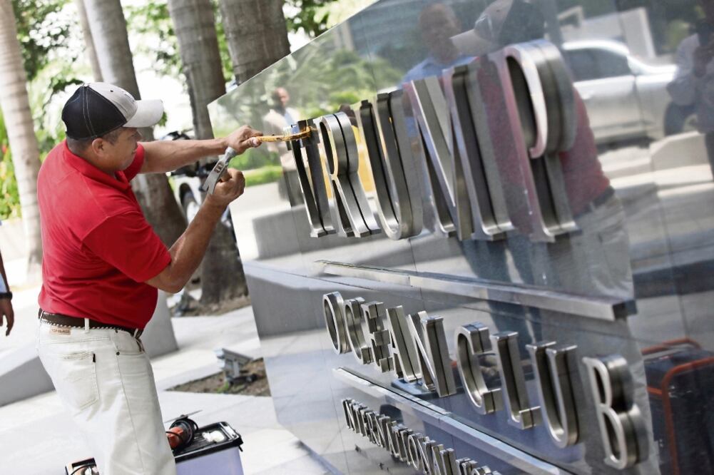 Un trabajador retira el letrero del Trump Ocean Club, mientras unidades de la policía nacional y representantes del Órgano Judicial de Panamá realizan un operativo en el edificio. Un juzgado panameño ordenó la expulsión de la Organización Trump.