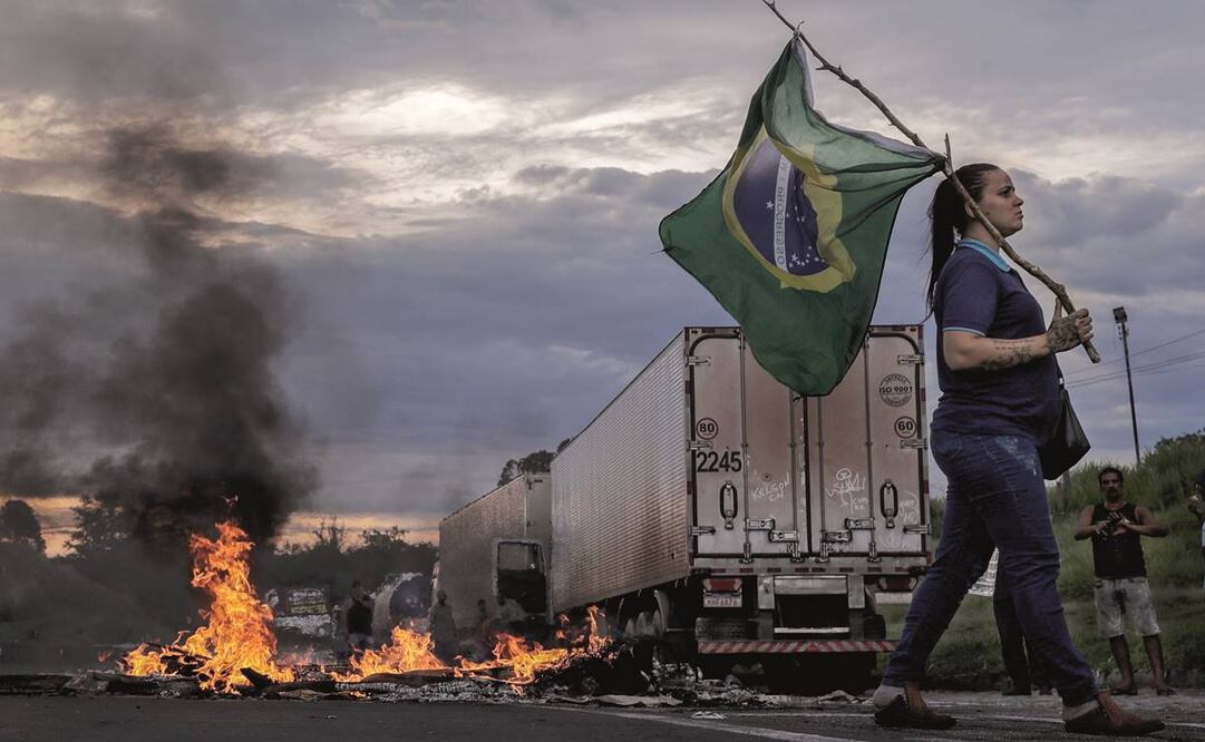 Una mujer sostiene una bandera de Brasil durante el bloqueo de camioneros en la carretera Presidente Dutra, cerca de Volta Redonda, en apoyo a Bolsonaro. Foto: Antonio Lacerda/ EFE