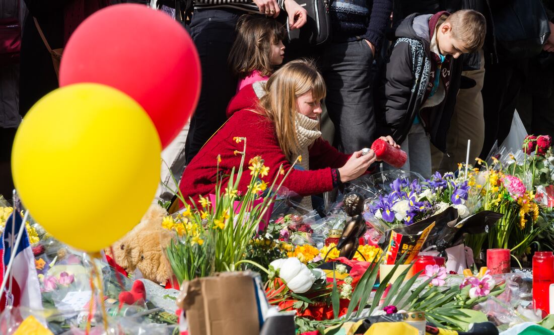 Una mujer enciende una vela en el monumento improvisado en la Place de la Bourse en Bruselas (AP)