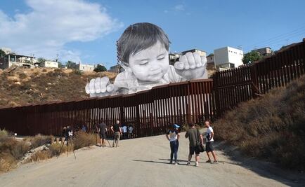 Artista levanta niño gigante en muro de EU y México