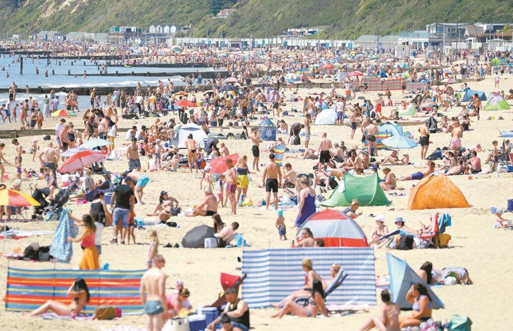 La gente disfruta del sol en la playa de Bournemouth, en Inglaterra, después de que se flexibilizaron algunas restricciones impuestas para frenar la propagación de Covid-19. GLYN KIRK. AFP