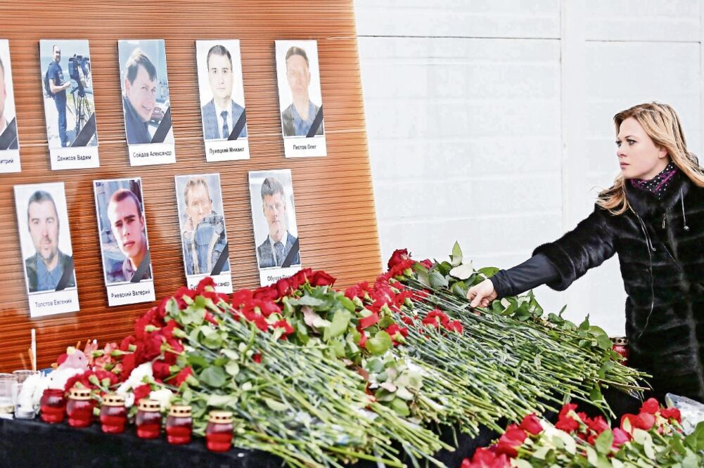 Una mujer dejó ayer flores en un altar con los retratos de los nueve periodistas rusos que fallecieron en el accidente del avión Tu-154 (SERGEI ILNITSKY. EFE)