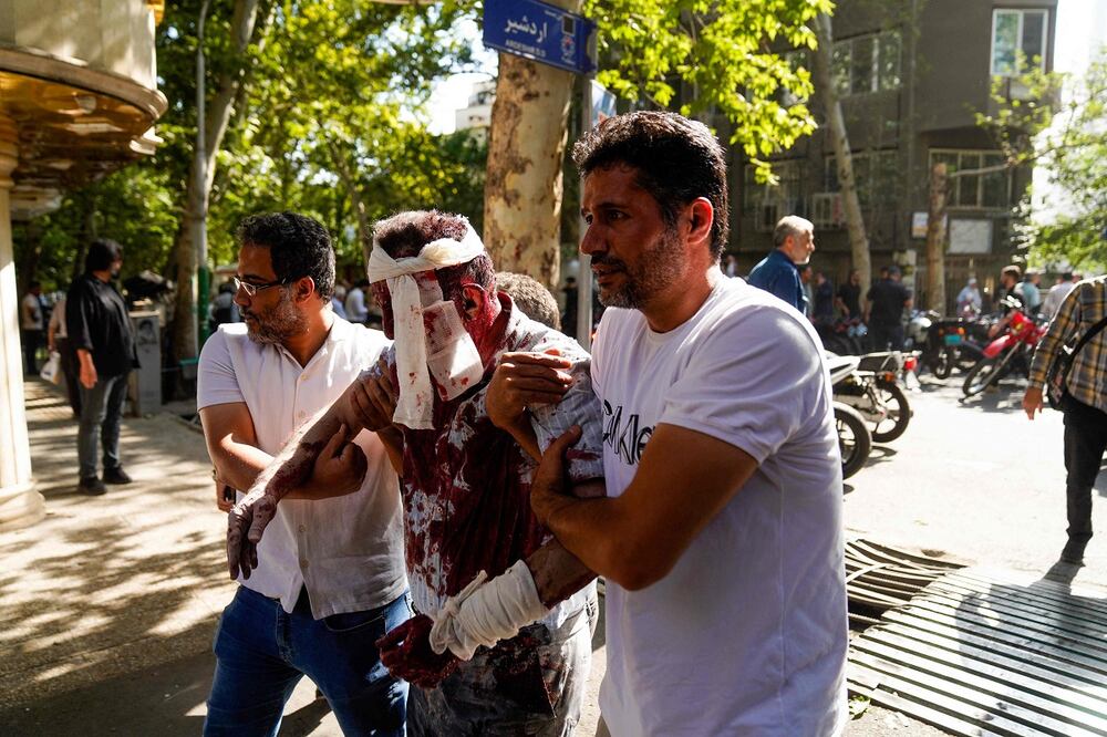 Iraníes ayudan a un hombre herido en un ataque israelí, en el centro de Teherán. FOTO: AFP