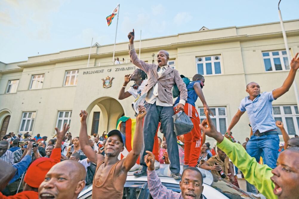 Zimbabuenses festejan afuera del Parlamento, en Harare, tras darse a conocer la noticia de la renuncia del presidente Robert Mugabe (BEN CURTIS. AP)