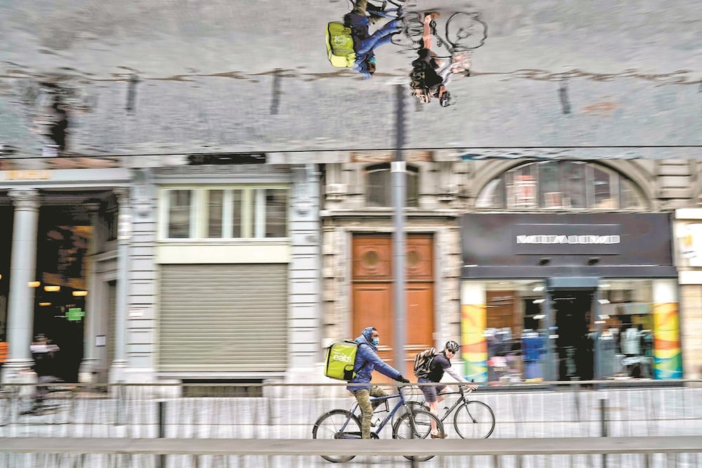 Un ciclista del servicio de entrega de comida a domicilio recorre las calles de Bruselas. En medio del confinamiento, algunos repartidores son obligados por los narcotraficantes para entregar drogas a los clientes. Foto: KENZO TRIBOUILLARD. AFP