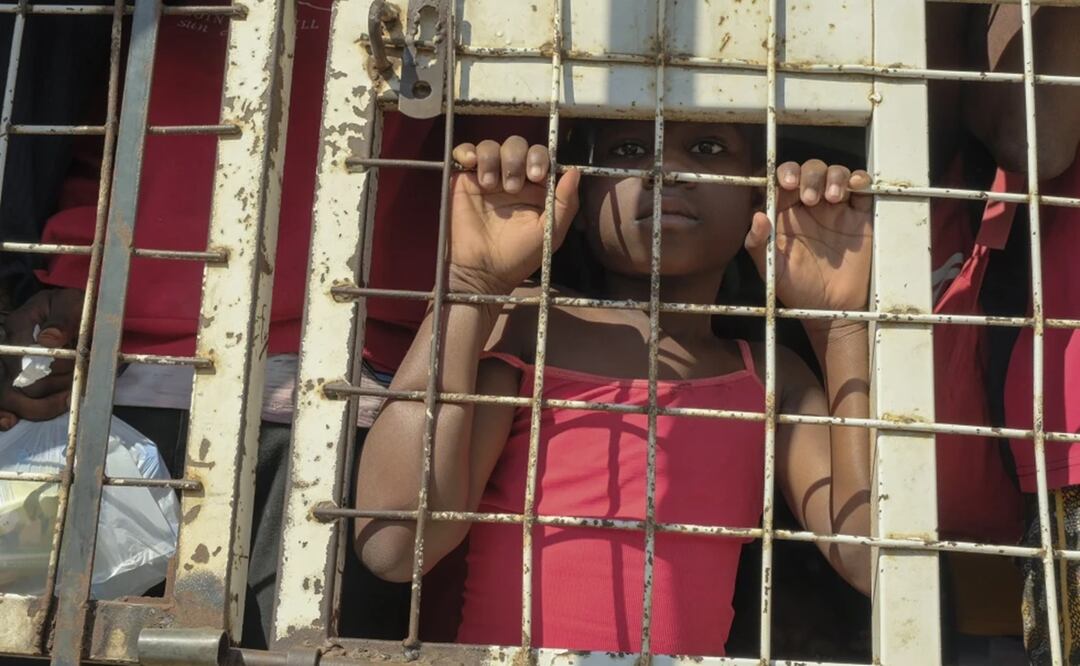 Un niño junto con personas detenidas para ser deportadas hacia Haití, en un camión policial, en un puente que conecta a Dajabón, República Dominicana, con Haití. Foto: AP