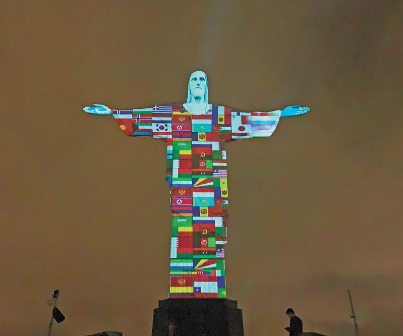 Banderas de los países afectados por el coronavirus se proyectan en el Cristo Redentor, en Río de Janeiro. FLORIAN PLANCHEUR. AFP