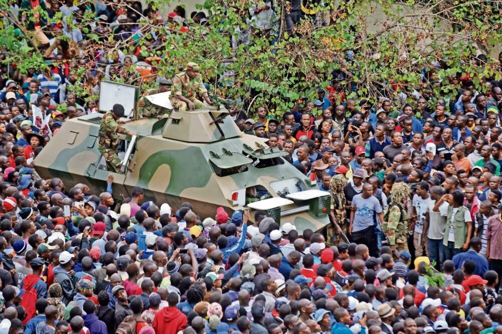 Levantamiento. Tanques militares pasaron entre los manifestantes en la protesta en contra del presidente Robert Mugabe. (BEN CURTIS. AP)