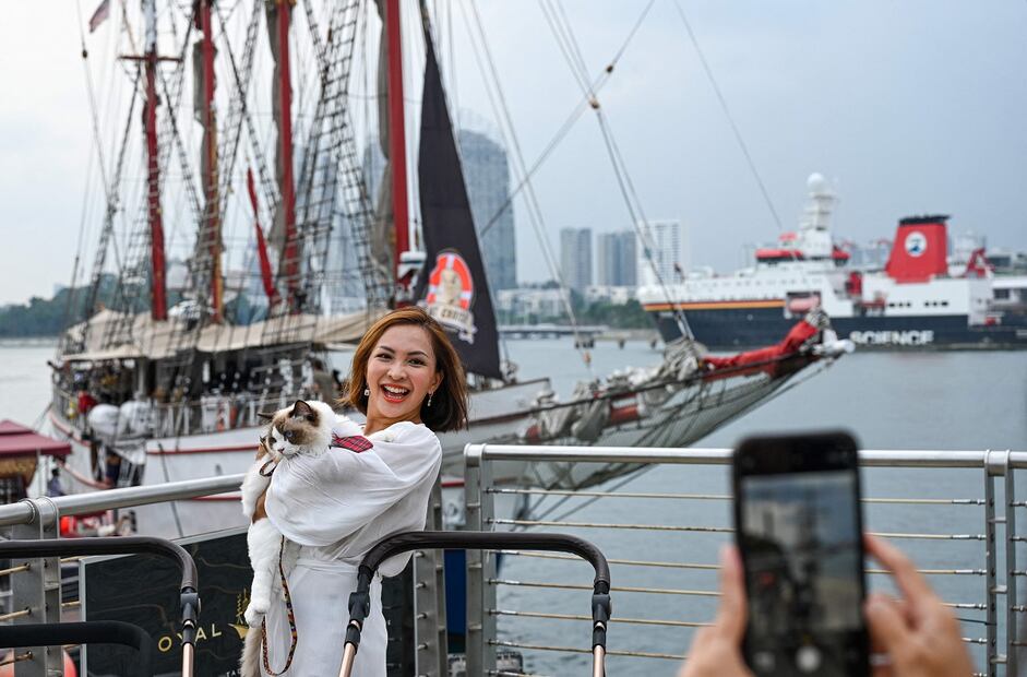 Una visitante posa para una foto con su gato frente al Royal Albatross, un barco alto de lujo que ofrece experiencias gastronómicas y de navegación en las aguas de Singapur y donde se permiten mascotas. Foto: AFP