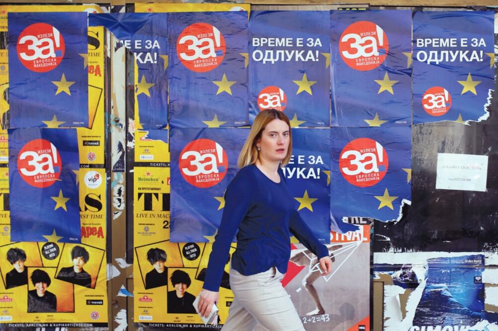 Propa ganda. Una mujer pasa cerca de imágenes que llaman a votar por el “sí” en el referéndum, en Skopje. Foto: OGNEN TEOFILOVSKI. REUTERS