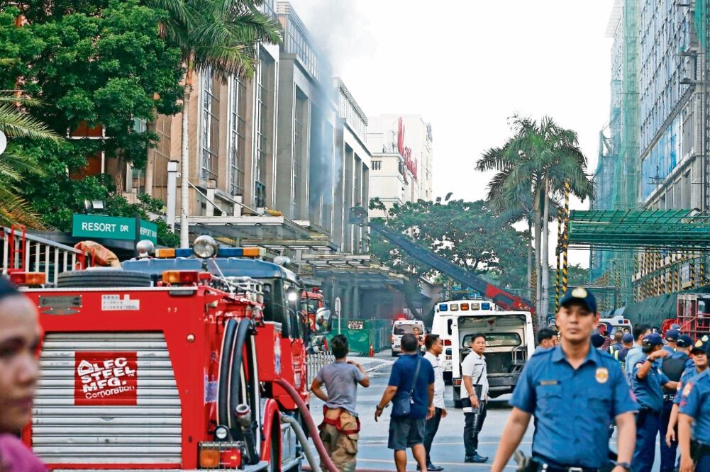 Policías vigilan este viernes los alrededores del hotel-casino Resort World Manila, de donde aún se ve salir humo, tras el incidente del viernes que las autoridades atribuyeron a un aparente intento de robo (ROLEX DELA PENA. EFE)