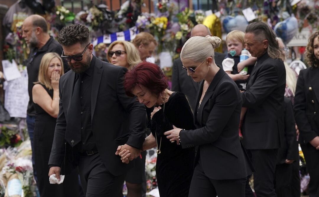 La familia de Ozzy Osbourne reacciona mientras deposita y observa las flores dejadas en el banco del puente Black Sabbath en Broad Street en memoria del líder de Black Sabbath, Ozzy Osbourne, antes de su cortejo fúnebre, en Birmingham, Inglaterra.
Foto: Joe Giddens/PA via AP.