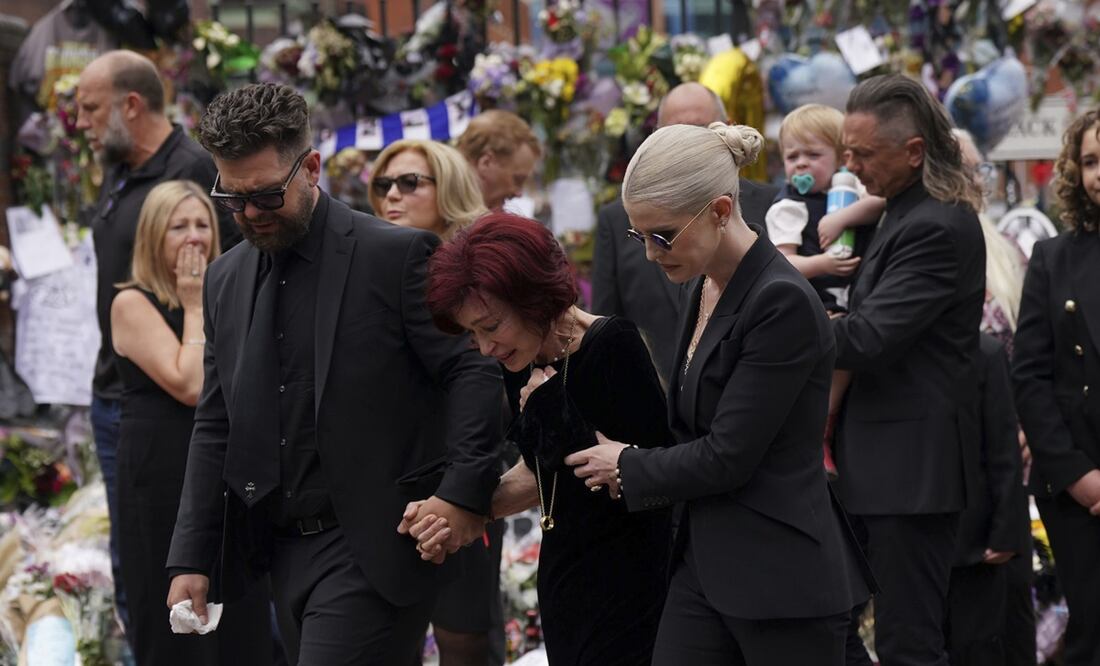 La familia de Ozzy Osbourne reacciona mientras deposita y observa las flores dejadas en el banco del puente Black Sabbath en Broad Street en memoria del líder de Black Sabbath, Ozzy Osbourne, antes de su cortejo fúnebre, en Birmingham, Inglaterra.
Foto: Joe Giddens/PA via AP.
