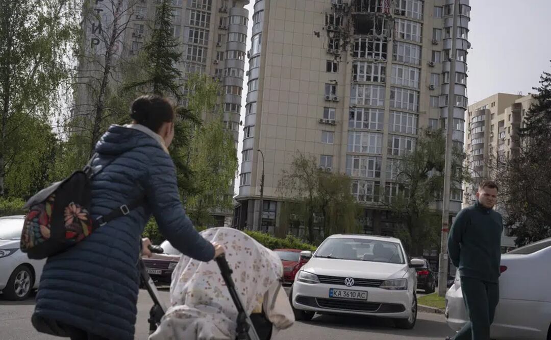 Gente pasa junto a un edificio de apartamentos dañado por restos de un dron derribado durante un ataque ruso la noche anterior en Kiev, Ucrania. Foto: AP