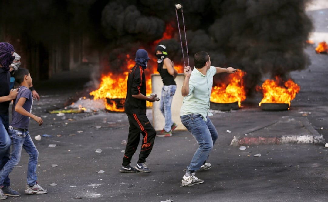 Manifestantes palestinos lanzan piedras hacia soldados israelíes durante un día más de enfrentamientos registrados en la ciudad cisjordana de Hebrón (Foto: EFE)