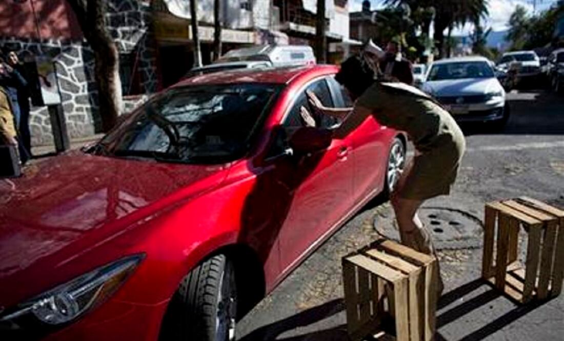 Arturo Hernández, wearing a dress and heels, implores a double-parked driver to move his car from a clogged street outside the ITESM in Mexico City. (Photo: AP)