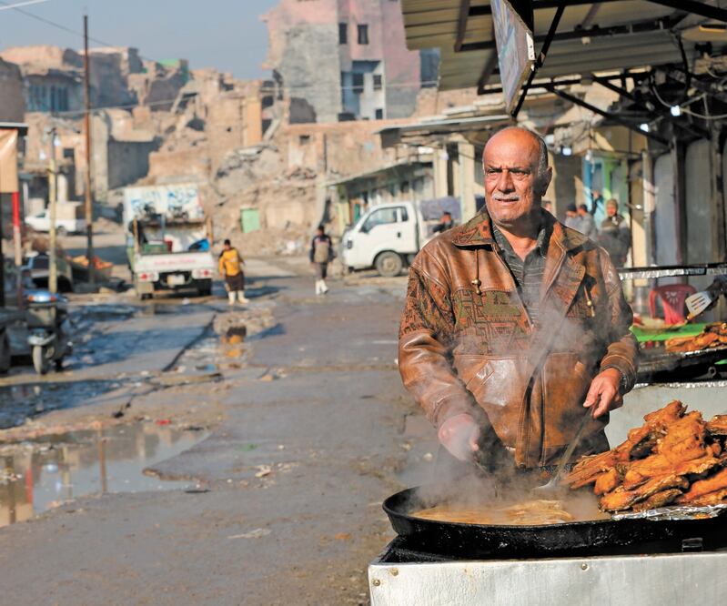 Un hombre vende pescado frito afuera del mercado de al-Attareen, en la ciudad antigua de Mosul, Irak, el pasado 23 de diciembre. XINHUA