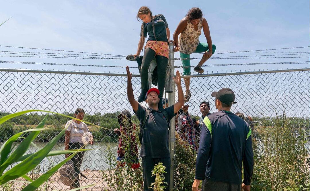 Migrantes se ayudan a trepar la cerca que separa a México de Estados Unidos, en Eagle Pass, Texas. Foto: AFP
