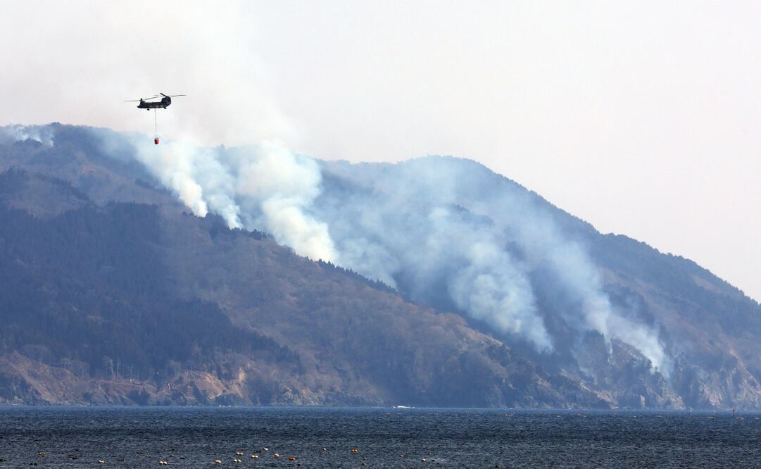 Un helicóptero militar ayuda en los esfuerzos de extinción de incendios mientras el humo se eleva desde las colinas de Ofunato, prefectura de Iwate, noreste de Japón, 28 de febrero de 2025. Foto: EFE