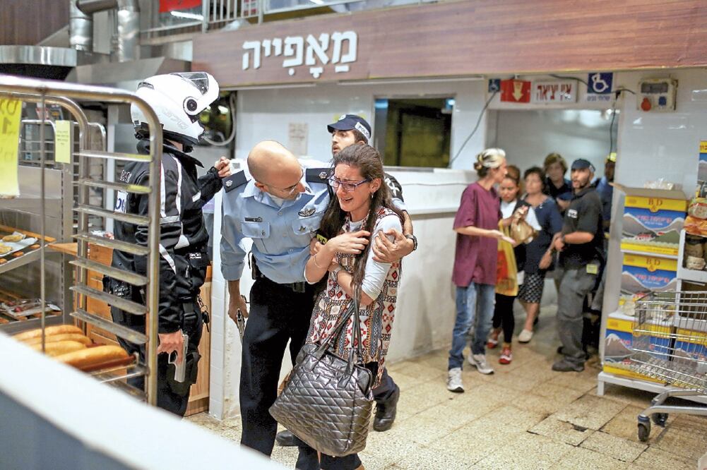 Un soldado israelí consuela a una mujer en la central de autobuses de Jerusalén, luego de que un palestino apuñalara a una persona (NOAM MOSKOWITZ. REUTERS)
