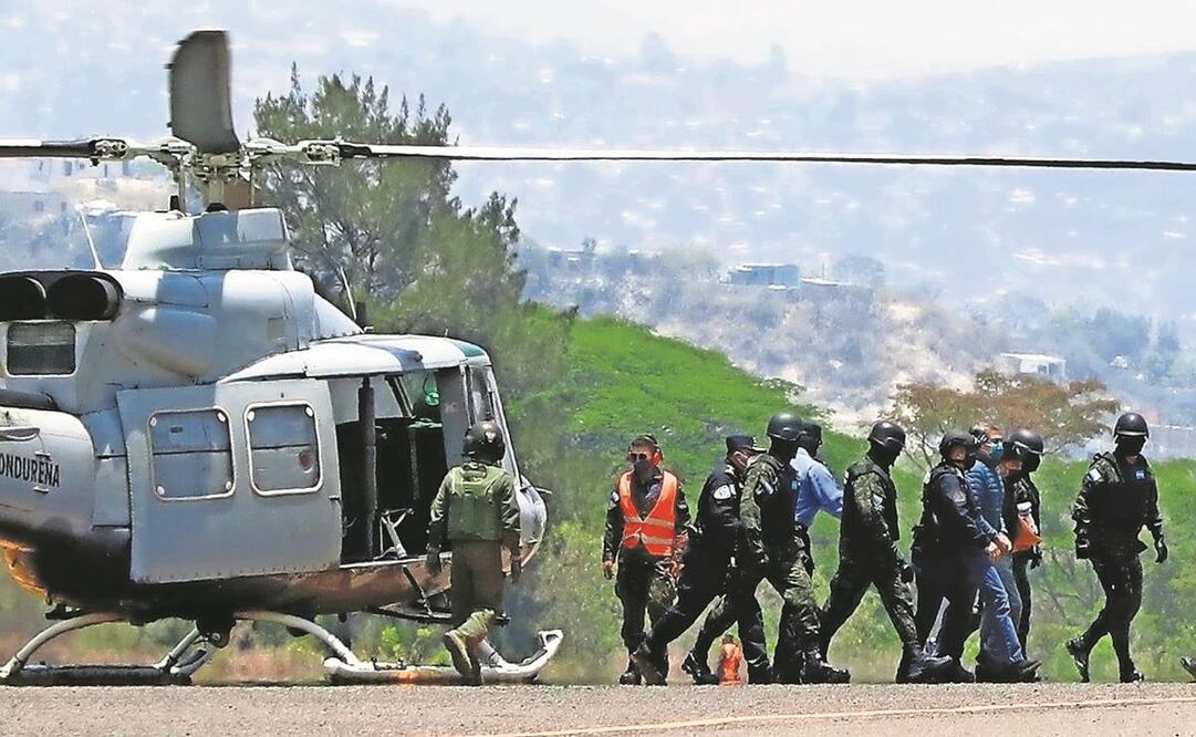 El expresidente hondureño Juan Orlando Hernández (der.), esposado y escoltado por soldados y policías al llegar a una base de la Fuerza Aérea en Tegucigalpa, Honduras, en abril de 2022.