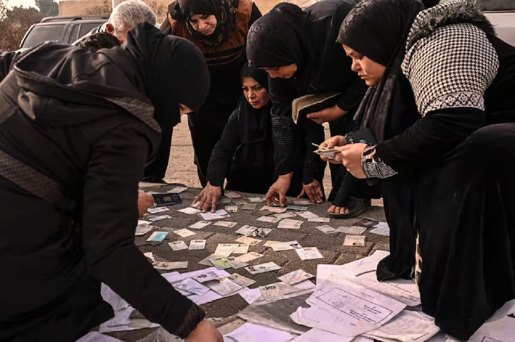 Mujeres buscan en documentos información sobre sus familiares desaparecidos, en el aeropuerto militar de Mazzeh, en las afueras de Damasco. Foto: AFP