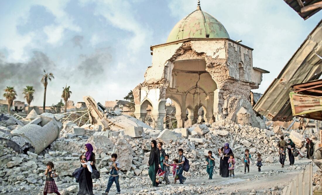Civiles iraquíes desplazados caminan sobre los restos de las mezquita al-Nuri, mientras las fuerzas del gobierno combaten al Estados Islámico. (FELIPE DANA. AP)