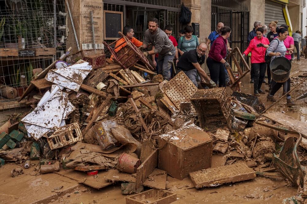 La gente limpia el barro de una tienda afectada por las inundaciones en Chiva, España, el viernes 1 de noviembre de 2024. Foto: AP