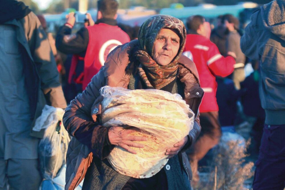 Una mujer siria proveniente de Aleppo carga sus pertenencias tras ser trasladada, junto con otras personas, a la población de Al-Rashideen (AMMAR ABDULLAH. REUTERS)