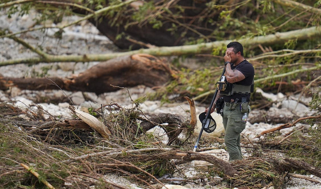 Un agente del sheriff se cubre el rostro mientras peina las orillas del río Guadalupe cerca de Camp Mystic, el sábado 5 de julio de 2025, en Hunt, Texas, después de que una inundación repentina arrasara la zona. Foto: AP