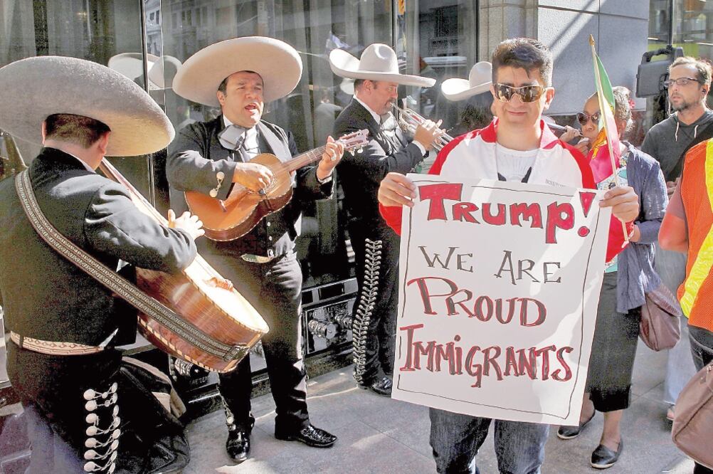 Manifestantes critican la postura antiinmigrante de Trump frente a uno de sus hoteles, en Toronto, el jueves, mientras los mariachis tocan (CHRIS HELGREN. REUTERS)