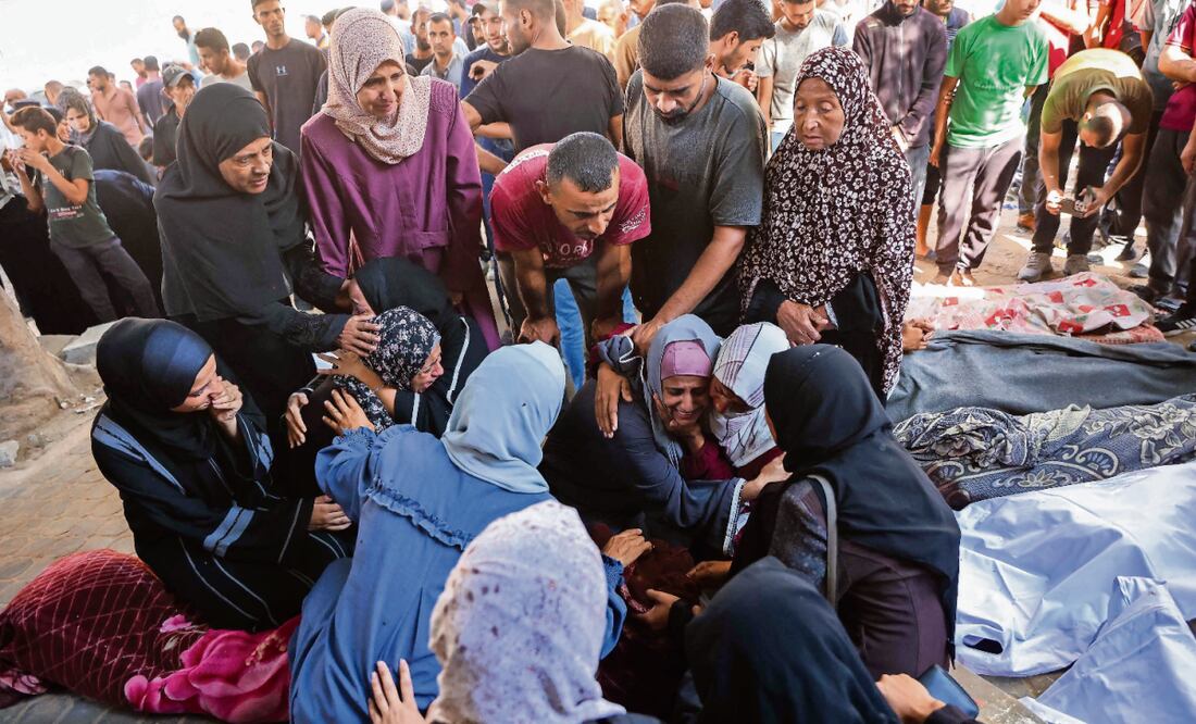 Palestinos junto a los cuerpos amortajados de sus familiares fallecidos en los ataques israelíes contra la Ciudad de Gaza, en el hospital Al-Shifa, el martes pasado. Foto: Omar Al-Qattaa / AFP