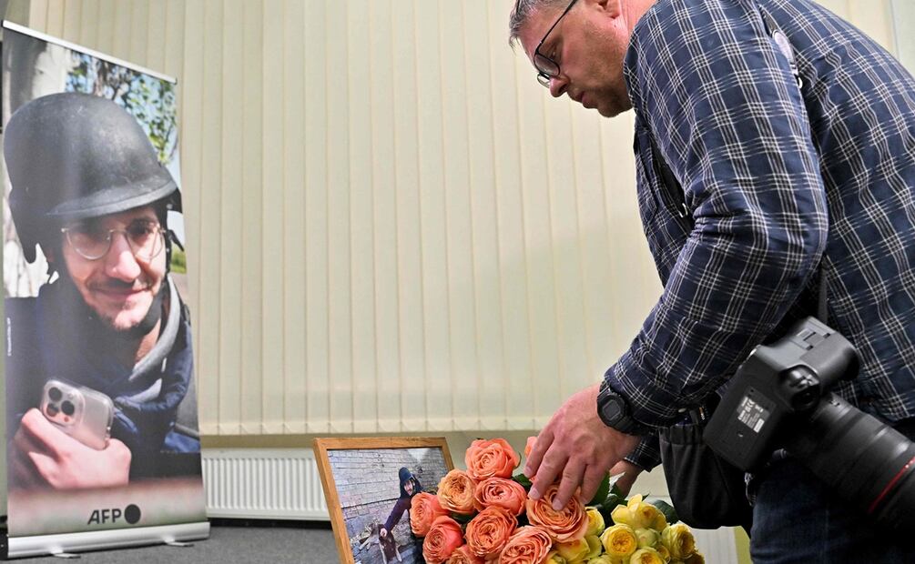 Un colega coloca flores junto a una pantalla que muestra una fotografía que muestra al periodista de AFP Arman Soldin. Foto: AFP