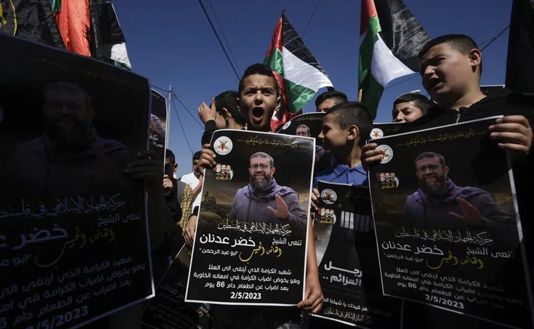 Niños palestinos ondean su bandera nacional y sostienen carteles que muestran a Khader Adnan que murió en una prisión israelí después de una huelga de hambre de casi tres meses. Foto: AP