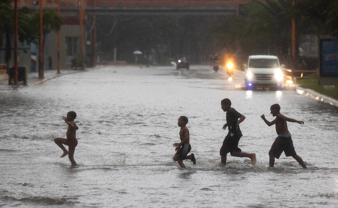 Un grupo de niños cruza por una calle inundada este jueves, en Santo Domingo (República Dominicana). Más de 647.000 usuarios están sin agua potable en la República Dominicana después de que las lluvias provocadas por la tormenta tropical Melissa afectaran decenas de acueductos, según datos ofrecidos por las autoridades oficiales. Foto: EFE