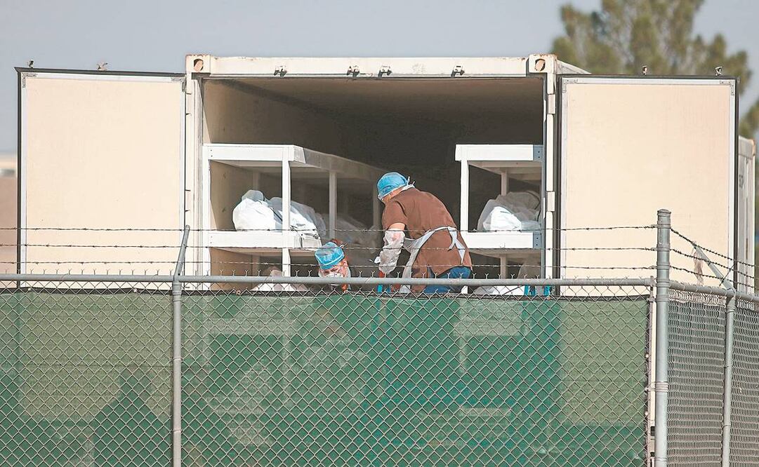 En un camión, usado como morgue, en El Paso, Texas, personal de sanidad coloca los cadáveres junto a un cementerio. La ciudad se encuentra al borde del colapso a causa del aumento de casos y decesos por el virus. Foto: Jesús Rosales. EFE