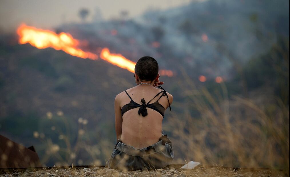 Una persona observa un incendio forestal que arrasa pastizales y zonas boscosas entre Potamia y Pispilounta, en la isla de Quíos, Grecia, el 12 de agosto de 2025. Foto: EFE