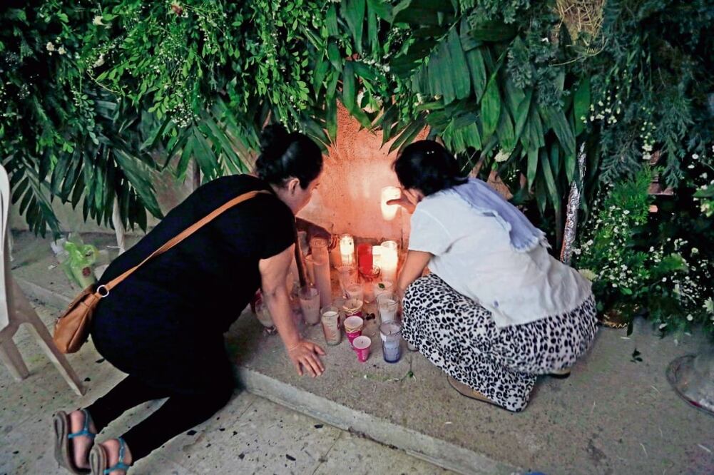 Dos mujeres encienden velas en la iglesia de Nuestra Señora de Fátima en Poza Rica, Veracruz, para pedir por el descanso de los dos sacerdotes hallados muertos (MARCO UGARTE. AP)