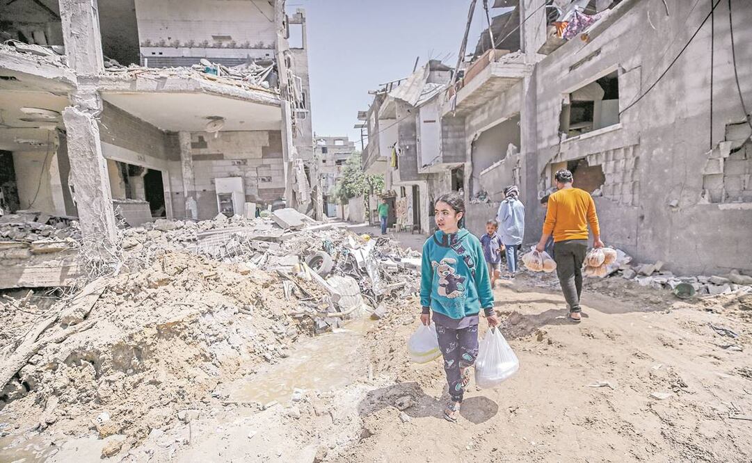 Palestinos caminan en medio de los escombros de sus casas, en Beit Hanun, en la Franja de Gaza. Foto: Mohammed Saber/ EFE.